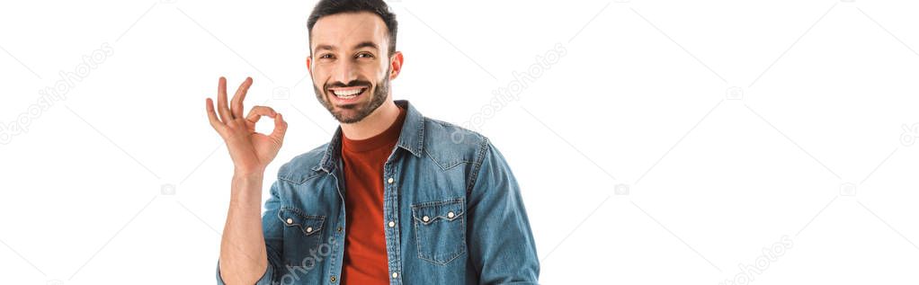 panoramic shot of smiling bearded man looking at camera and showing ok sign isolated on white