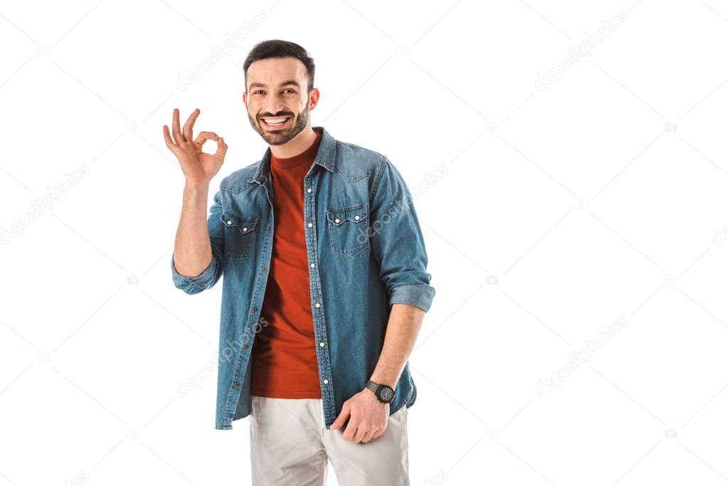 handsome cheerful man looking at camera and showing okay gesture isolated on white