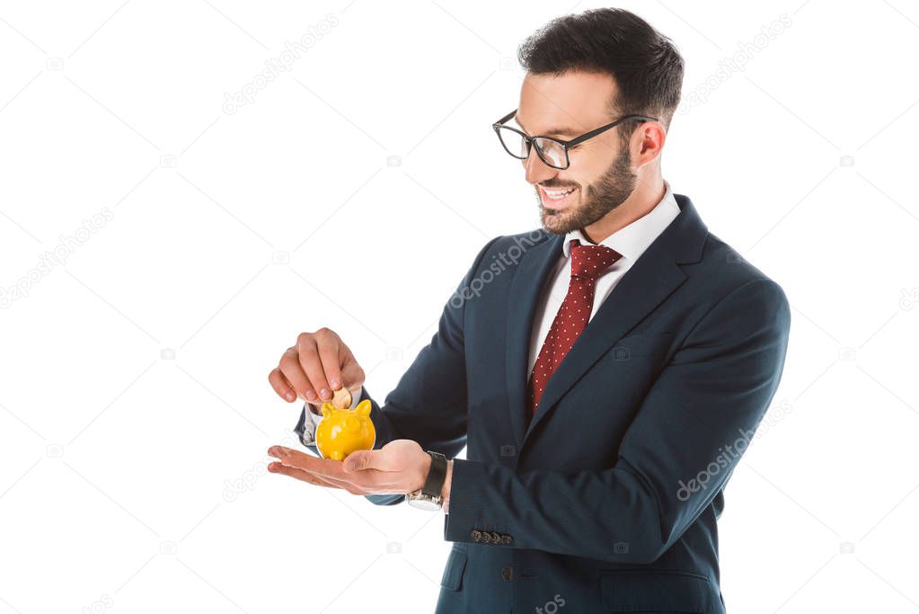 smiling businessman putting coin into piggy bank isolated on white
