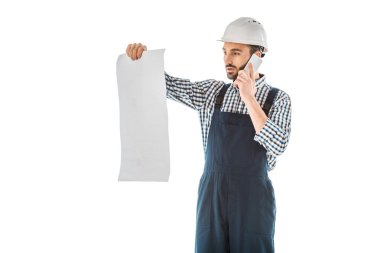 beyaz izole bina planı bakarken akıllı telefon üzerinde konuşurken özenli inşaat işçisi