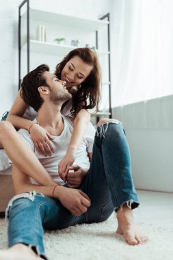 yakışıklı adam halı üzerinde oturan ve evde neşeli kız ile el ele tutuşuyor 