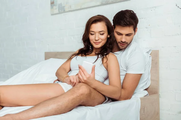 남자와 침대에 누워있는 스마트 사용하는 매력적인 — 스톡 사진