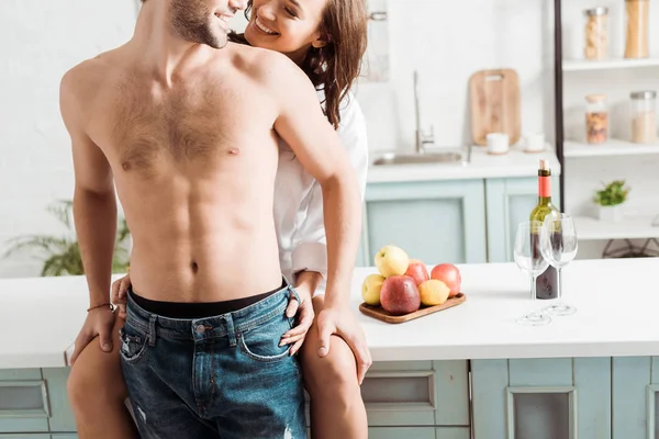 Mutfakta Oturan Gömleksiz Erkek Arkadaşı Bakarak Neşeli Kız Kırpılmış Görünümü — Stok fotoğraf