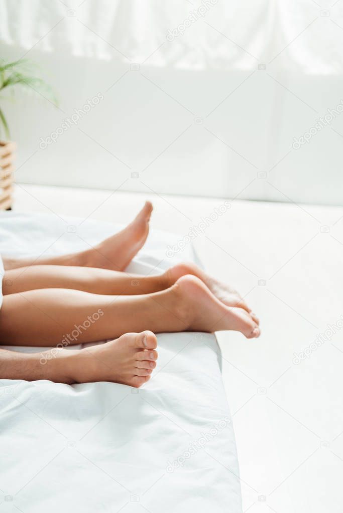 cropped view of barefoot on woman and man lying on bed 