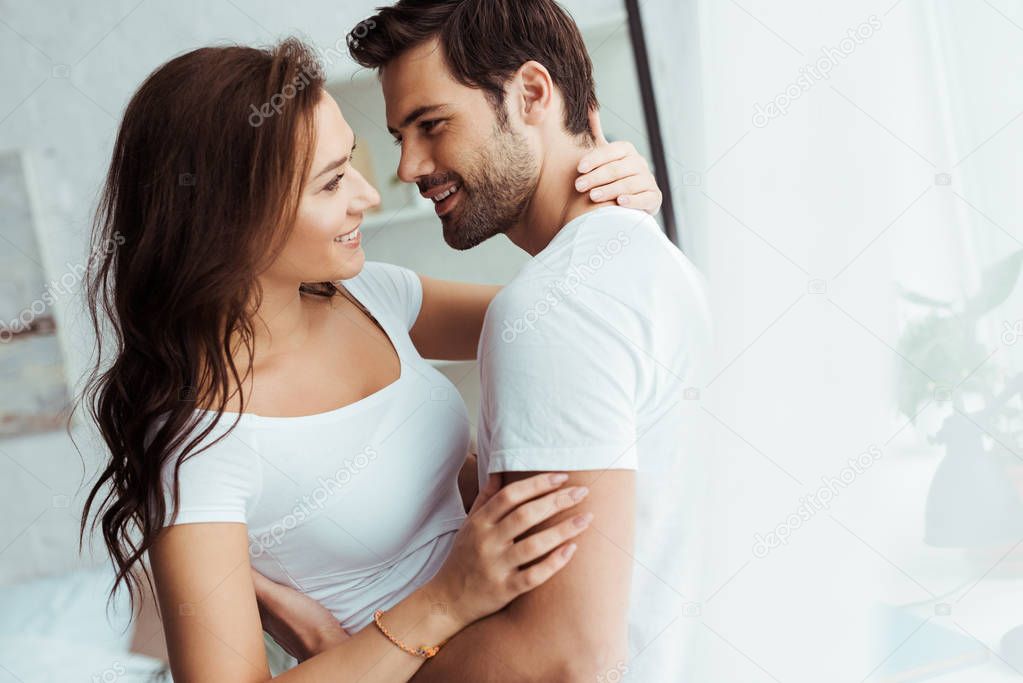 happy man looking at cheerful girl while hugging at home 