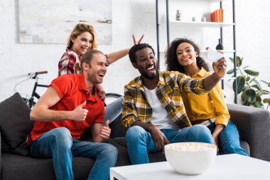 Pozitif mutlu çok ırklı arkadaşlar selfie çekmek ve evde eğlenmek