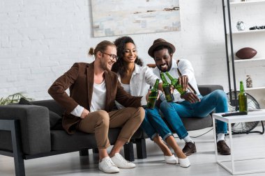 oturma odasında afrikalı-amerikalı kız ile tost neşeli çok kültürlü erkekler 