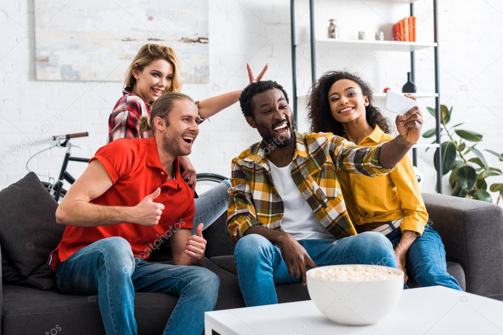 Positive happy multiethnic friends taking selfie and having fun at home