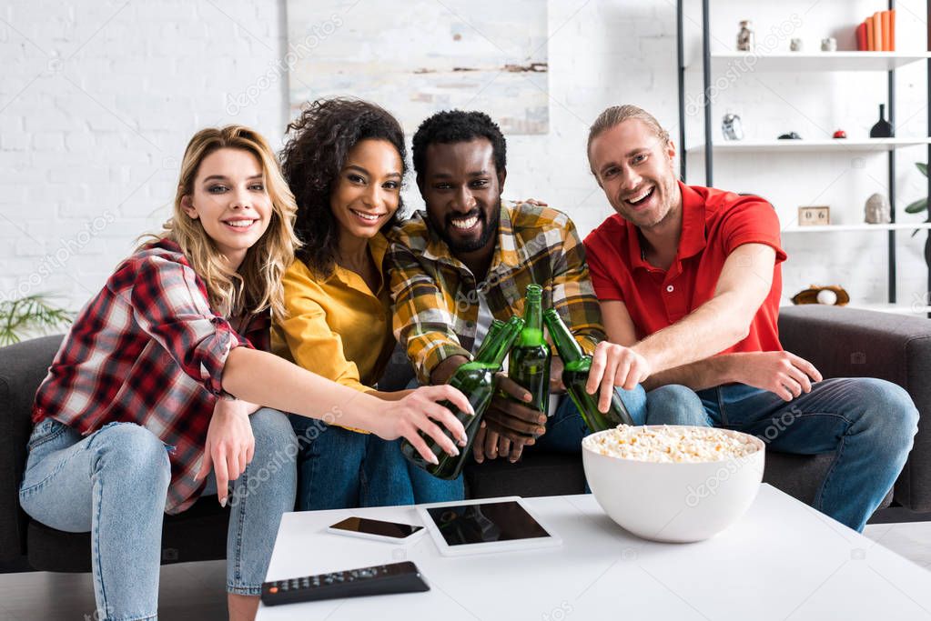 selective focus of cheerful multicultural friends toasting in living room  