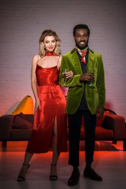 sarışın kadın ile ayakta ve şampanya cam tutan yakışıklı afro-amerikan adam 