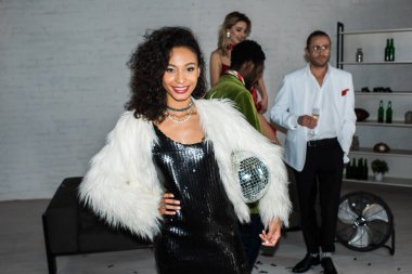 arkadaşlarının yanında dururken disko topu tutan Afrikalı-Amerikalı kız seçici odak