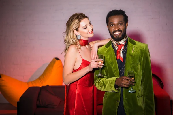 开朗和有吸引力的女人在红色礼服看着英俊的非洲美国男子与香槟玻璃 — 图库照片