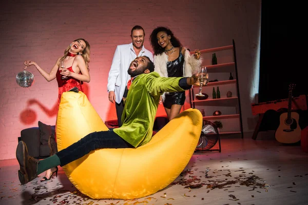 mutlu arkadaşlar yakın fasulye kötü sandalyede oturan Afrikalı Amerikalı adam düşük açı görünümü 