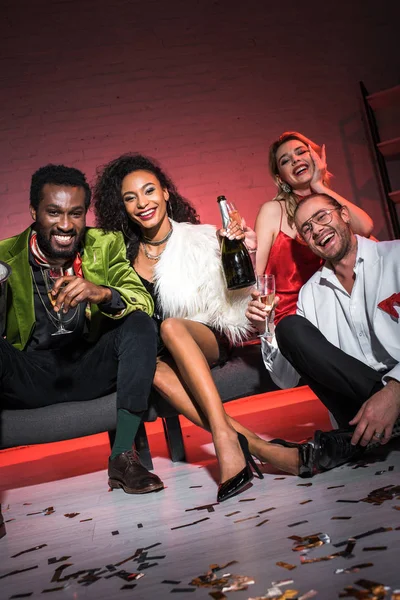 çok kültürlü arkadaşlarının yanında otururken şişe tutan Afrikalı-Amerikalı kadının düşük açı görünümü