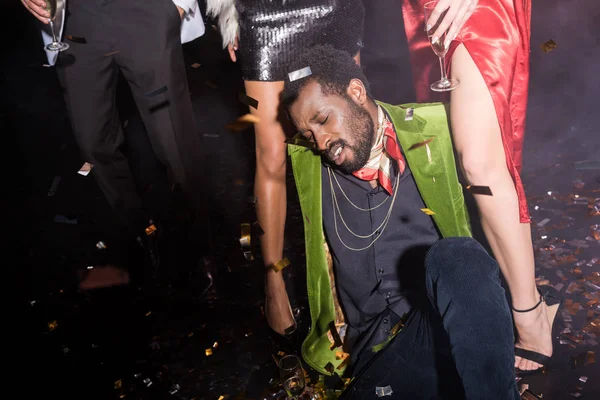 Пьяный Африканский Американец Закрытыми Глазами Лежащий Полу Блестящими Конфетти Рядом — стоковое фото