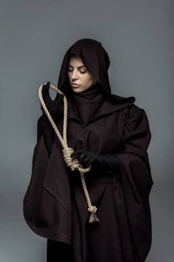 Ölüm kostümü giymiş bir kadın, gri ipte asılı duruyor.