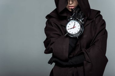 cropped view of woman in death costume holding alarm clock isolated on grey clipart