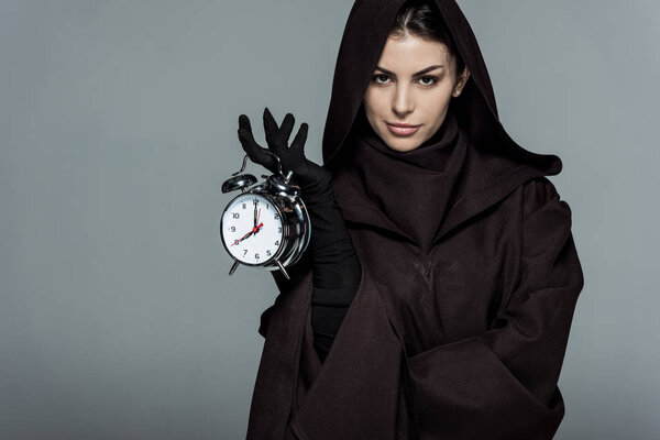 woman in death costume holding alarm clock isolated on grey