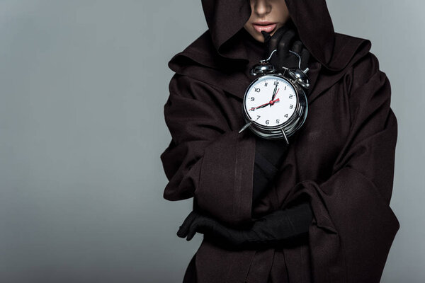 cropped view of woman in death costume holding alarm clock isolated on grey