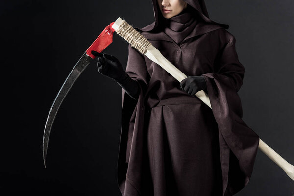 cropped view of woman in death costume holding scythe on black