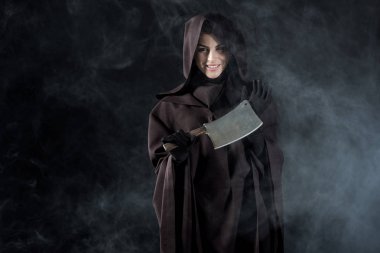 Ölü kostümlü kadın siyah satırı duman içinde tutuyor.