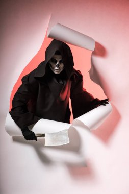 Ölü kostümlü kadın satırı tutuyor ve kağıtta delikten çıkıyor.