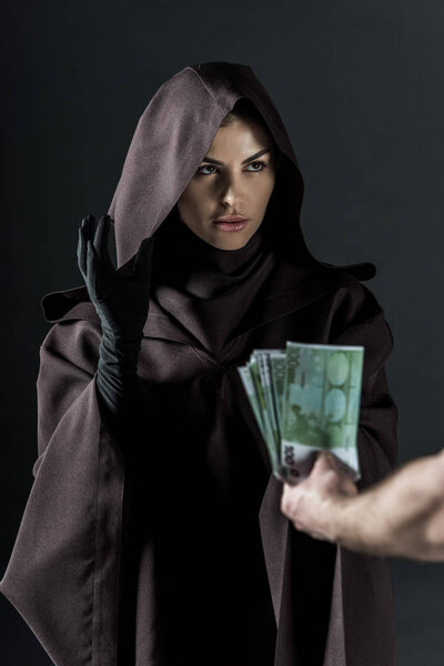 partial view of man giving euro banknotes to woman in death costume isolated on black