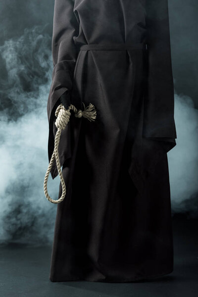 cropped view of woman in death costume holding hanging noose on black