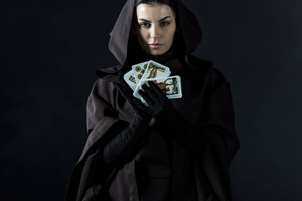KYIV, UKRAINE - APRIL 18, 2019: front view of woman in death costume holding tarot cards isolated on black