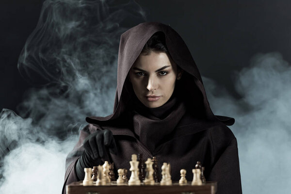 woman in death costume playing chess in smoke on black
