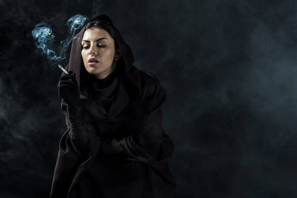 woman in death costume smoking cigarette on black