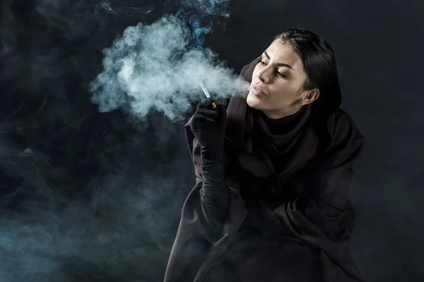 穿着死亡服装的女人在黑漆漆上抽烟 — 图库照片