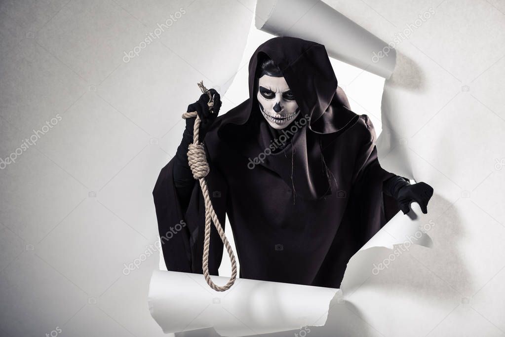 woman in death costume holding hanging noose and getting out of hole in paper