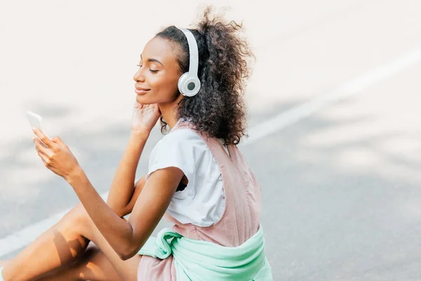 Leende Afrikansk Amerikansk Flicka Lyssnar Musik Hörlurar Och Använda Smartphone — Stockfoto