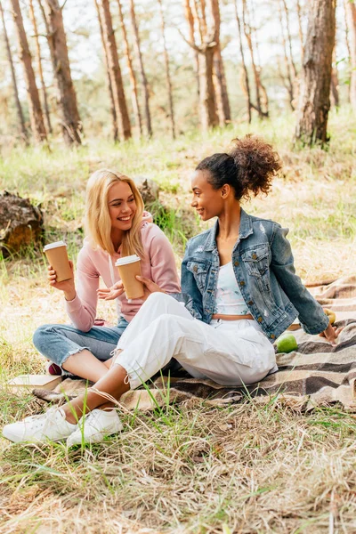 Two Multiethnic Friends Sitting Plaid Blanket Holding Paper Cups Coffee — Stock Photo, Image