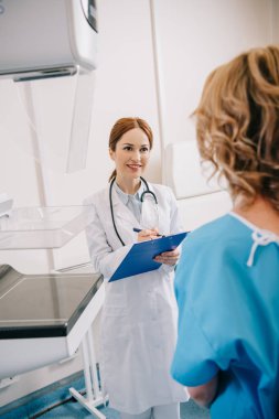 klinikte hastanın yakınındaki panoya gülümseyen radyograf yazma seçici odak