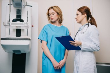x-ray makinesi nin yanında dururken üzgün kadın bakarak pano ile radyolog