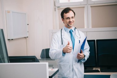 gülümseyen doktor pano tutarken başparmak gösteren ve kameraya bakarak