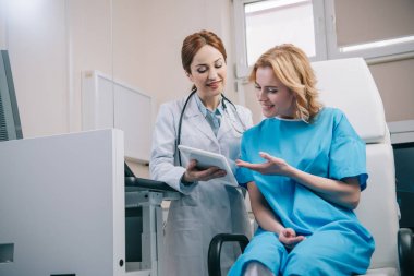 mutlu kadına tanı ile dijital tablet gösteren gülümseyen doktor 