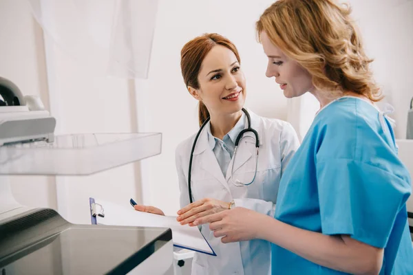 Lächelnder Radiologe Mit Klemmbrett Während Der Nähe Des Patienten Steht — Stockfoto