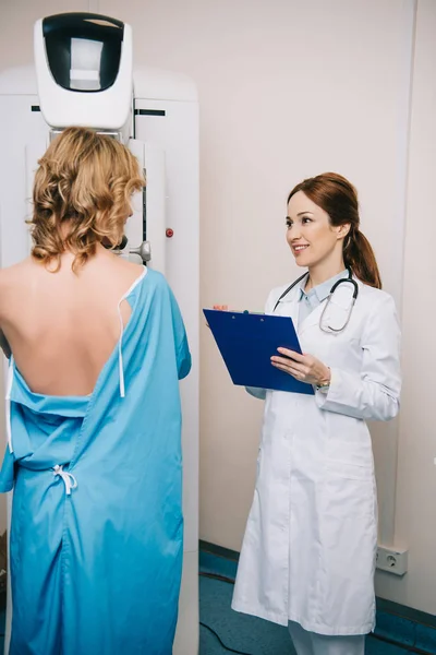 Glimlachende Radiograaf Holding Klembord Buurt Van Patiënt Maken Mammografie Test — Stockfoto
