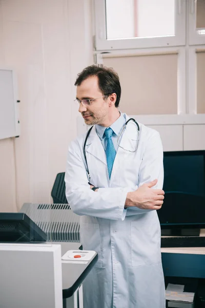 英俊的医生在白色外套和眼镜站在交叉的手臂在医院 — 图库照片