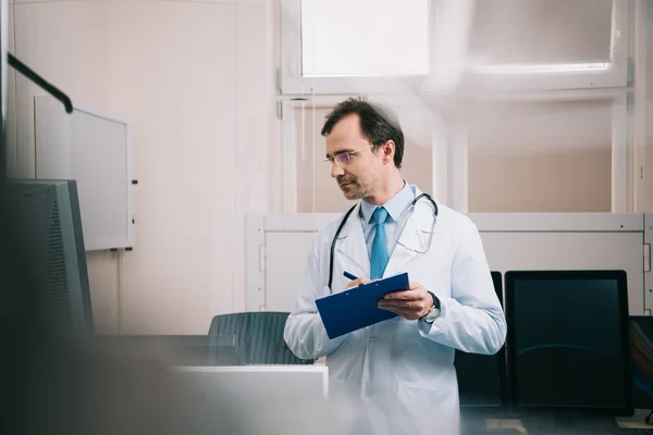 Enfoque Selectivo Del Médico Sonriente Escribiendo Portapapeles Mirando Hacia Otro — Foto de Stock