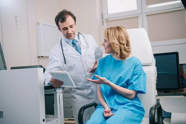 快乐的女人在医院与微笑的医生交谈 拿着数字平板电脑 — 图库照片