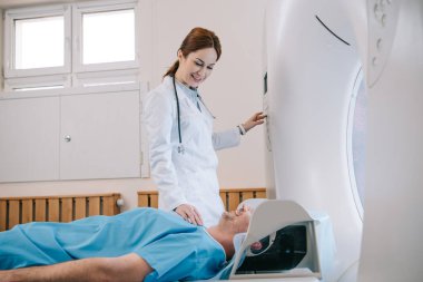 mr makinesinde tomografi teşhisi için adam hazırlayan güzel genç radyolog