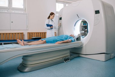 young radiographer operating ct scanner while preparing patient for tomography