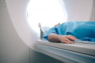 selective focus of patient lying on ct scanner bed during tomography test clipart