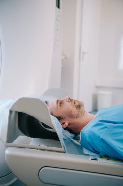handsome man lying on ct scanner bed during tomography diagnostics in hospital clipart
