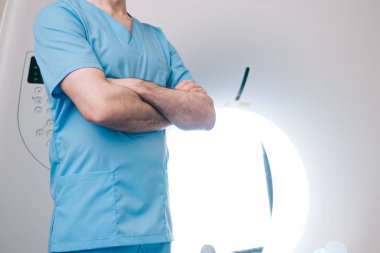 partial view of doctor standing with crossed arms near ct scanner  clipart