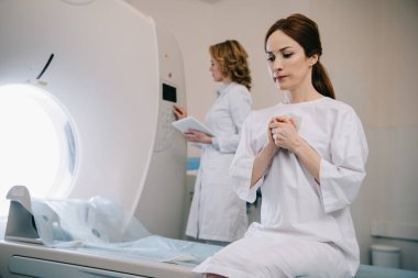 radyolog yakınında ct tarayıcı yatakta otururken dua endişeli kadının seçici odak
